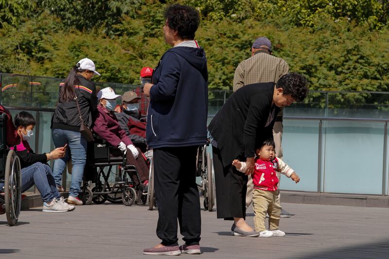 A woman plays with a child in a compound near a commercial office building in Beijing.