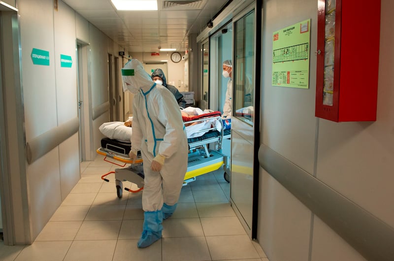 Medics wearing special suits to protect against coronavirus transfer a patient.