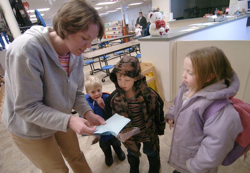 Upon picking her children up from daycare, Melissa Bartzen looks at a book (made by her son Adam) with her sons 3 year-old David, 5 year-old Adam, and her daughter 6 year-old Rachel.  Plain City resident Melissa Bartzen is a single mother who is currently
