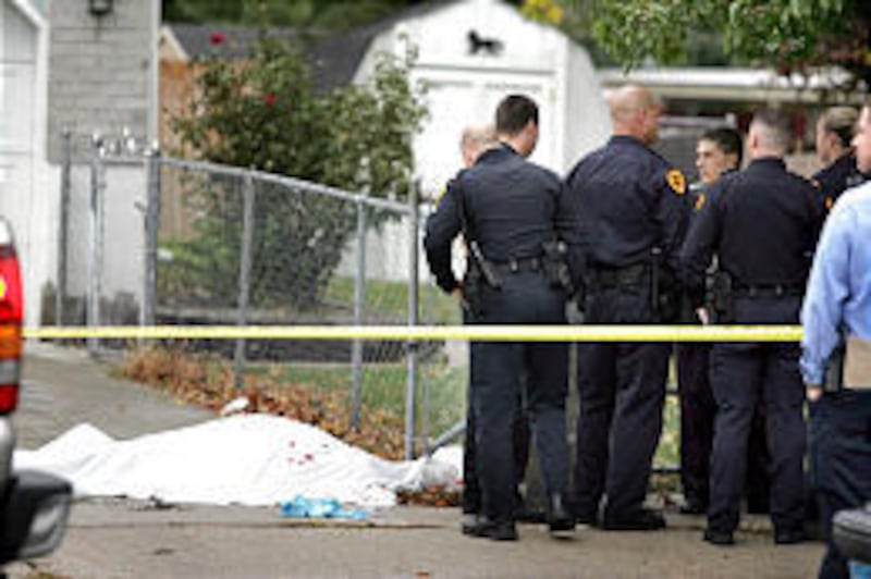 Salt Lake City police officers confer near the body of a 21-year-old man who was fatally shot in Rose Park Thursday by an unknown pedestrian.