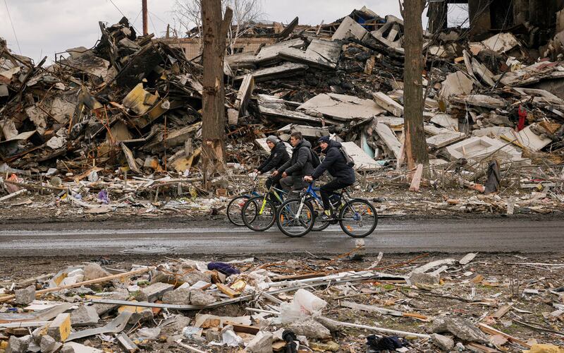 Men ride bicycles by a destroyed apartment in Borodyanka, Ukraine.