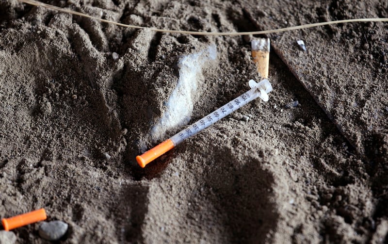 A discarded syringe sits in the dirt under a highway overpass where drug users are known to congregate in Everett, Wash.