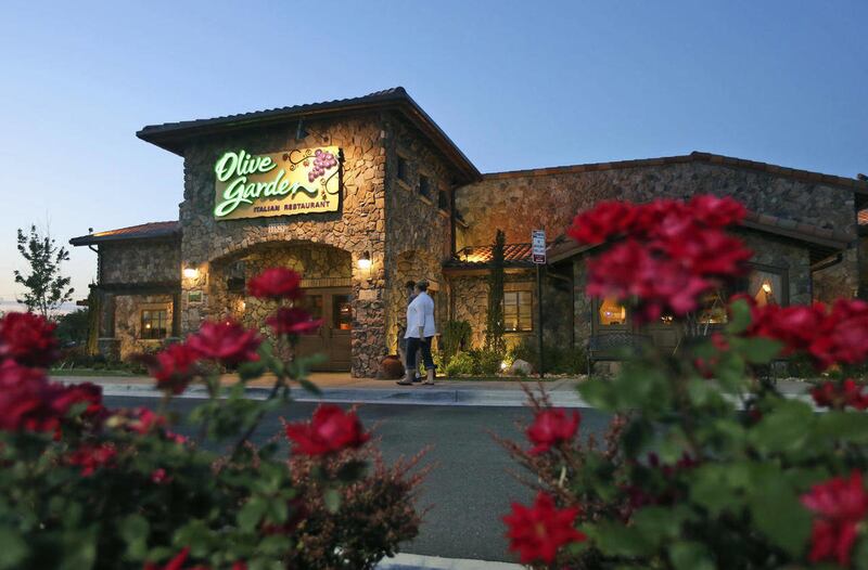 In this May 22, 2014 photo, patrons enter an Olive Garden Restaurant in Short Pump, Va. Olive Garden is hurting itself by piling on too many breadsticks, according to an investor who’s disputing how the restaurant chain is run.
