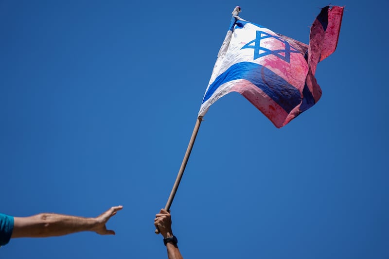 A demonstrator waves a colored Israeli flag during a protest outside the Knesset, Israel’s parliament, in Jerusalem.