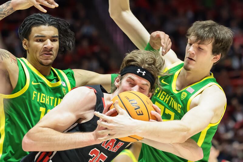 Utah center Branden Carlson comes under pressure from Oregon Ducks players during a game at the Huntsman Center.