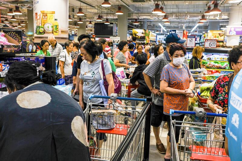 Shoppers wait in line to pay at a supermarket in Singapore, Tuesday, Mar. 17, 2020. Singaporeans were seen buying food supplies in supermarkets following neighboring Malaysia’s announcement of a nationwide lockdown due to the coronavirus to begin Wednesday which could affect the flow of food supplies to the city state. (AP Photo/Ee Ming Toh)