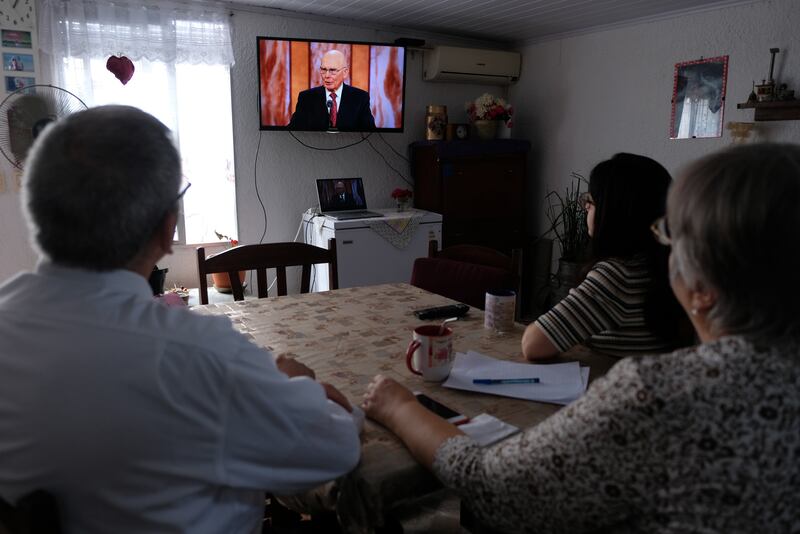 A family in Uruguay watches a session of general conference while seated around their kitchen table.