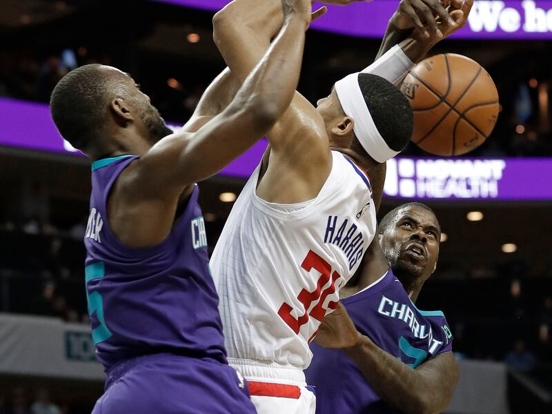 Los Angeles Clippers' Tobias Harris (34) is fouled as he drives between Charlotte Hornets' Kemba Walker, left, and Marvin Williams, right, during the second half of an NBA basketball game in Charlotte, N.C., Tuesday, Feb. 5, 2019. (AP Photo/Chuck Burton)