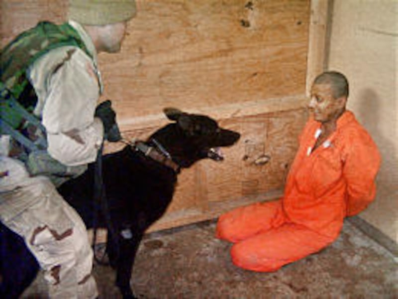 A U.S. soldier, identified in a military court-martial as Sgt. Michael J. Smith, holds a dog in front of an Iraqi detainee at Abu Ghraib prison outside of Baghdad. Smith was found guilty at the court-martial Tuesday.