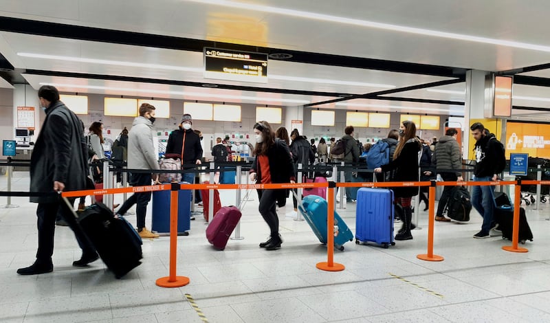 In this Dec. 20, 2020, file photo, passengers queue for check-in at Gatwick Airport in West Sussex, England, south of London.