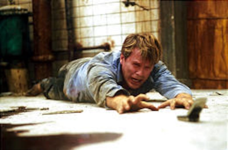 Dr. Lawrence Gordon, played by Cary Elwes, reaches for a cell phone after finding himself chained to a pipe in a decrepit chamber in "Saw."