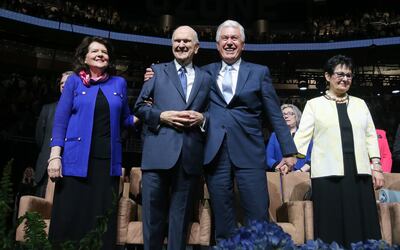 President Russell M. Nelson is hugged by Elder Dieter F. Uchtdorf of the Quorum of the Twelve Apostles as their wives, Sister Wendy Nelson and Sister Harriet R. Uchtdorf, stand prior to leaving the stage at the Amway Center in Orlando, Florida, after a de