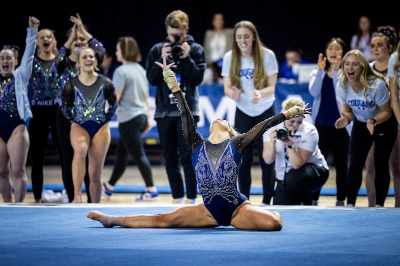 BYU gymnasts react after a teammate finishes floor routine against Utah State during 2023 season.