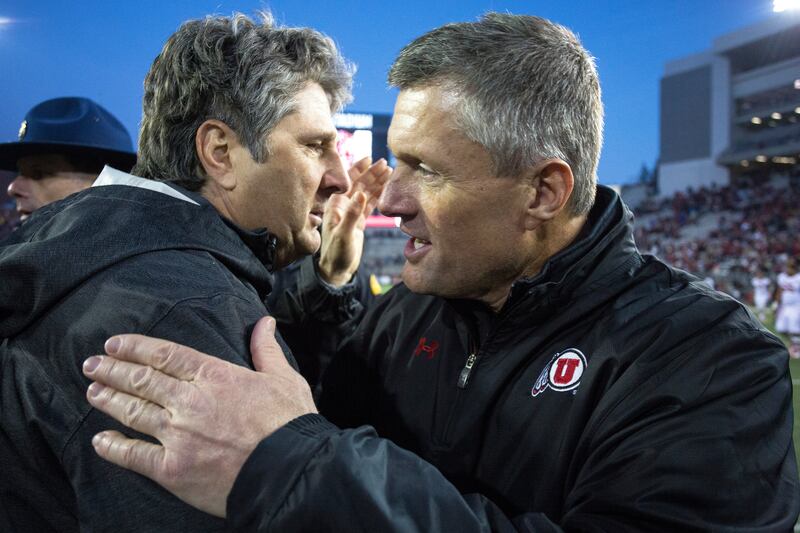 Washington State head coach Mike Leach, left, and Utah head coach Kyle Whittingham shakes hands after a college football game.