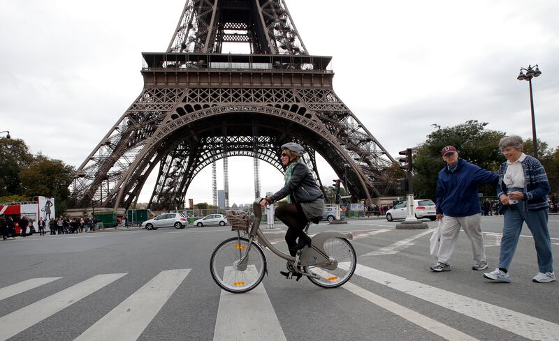 Woman cycles past Eiffel Tower in Paris, France