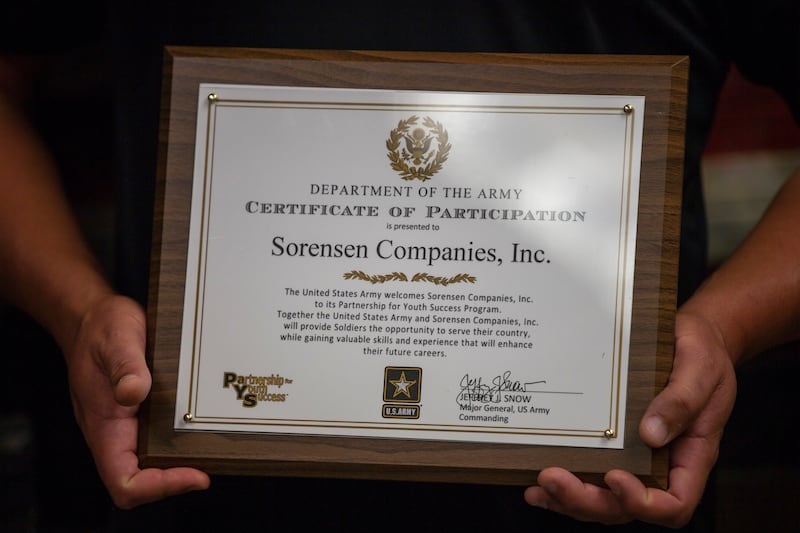 Chad Sorensen, president of Sorensen Companies, Inc., holds a certificate as it partners with U.S. Army to attract, train and deploy talented young people who want to serve their country, but also want to help secure their future success once their Army s