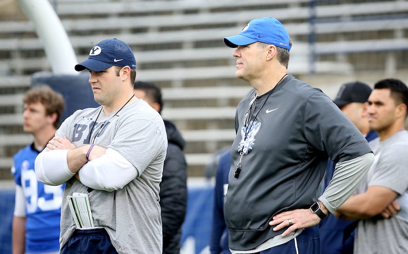 Offensive coordinator Jeff Grimes, right, and offensive line coach Ryan Pugh watch players warm up before the Blue-White Game at LaVell Edwards Stadium in Provo on Saturday, April 7, 2018.