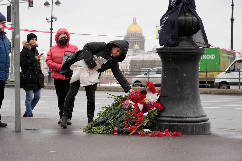 People lay flowers near the site of an explosion at the “Street Bar” cafe with the St. Isaac’s Cathedral in the background in St. Petersburg, Russia.