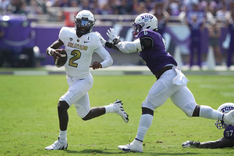 Colorado quarterback Shedeur Sanders (2) runs from TCU linebacker Jamoi Hodge (6).