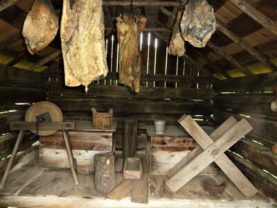 Hanging meat and tools dominate the plantation smokehouse interior.