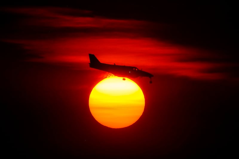 A plane passes in front of the glowing sun as it makes its final approach at the Salt Lake City International Airport on Monday, Oct. 5, 2020.