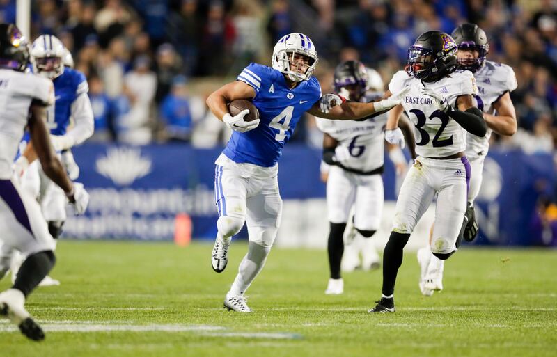 BYU running back Lopini Katoa ,wearing blue, runs the ball while stiff-arming East Carolina Pirates Julius Wood