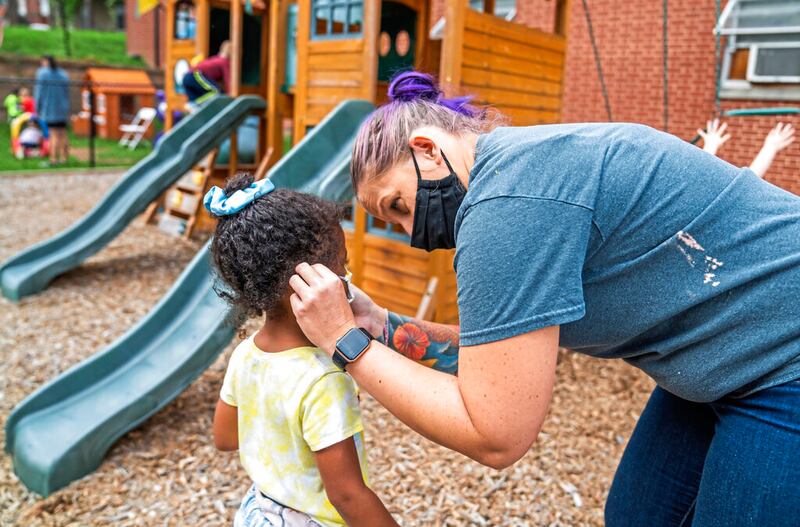 Assistant director Nicole Gross helps Naomi Adams with her face mask.