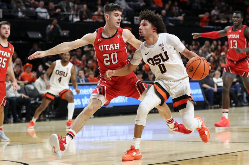 Oregon State guard Jordan Pope (wearing white) drives to the basket as Utah guard Lazar Stefanovic (wearing red) defends
