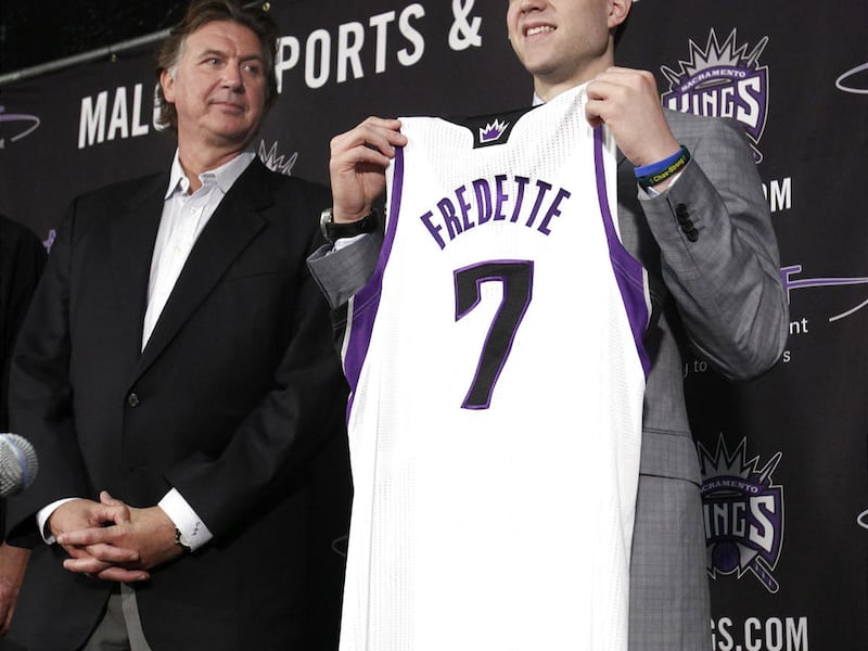 Jimmer Fredette, the Sacramento Kings first round draft pick, the 10th overall, in the NBA draft, held Thursday, holds his jersey up as Kings President of Basketball Operations Geoff Petrie, looks on during a news conference in Sacramento, Calif., Satu