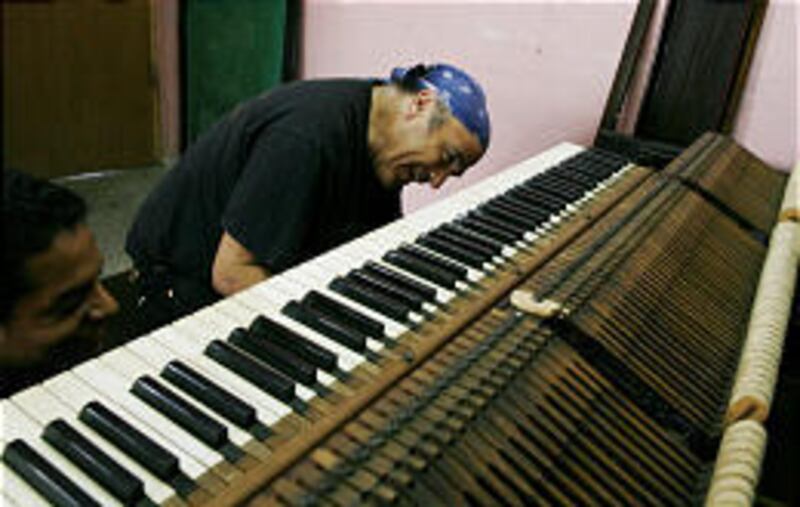 American piano tuner Benjamin Treuhaft, back, checks a piano keyboard in Havana on Thursday.