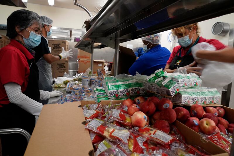Los Angeles Unified School District food service workers prepackage hundreds of free school lunches in plastic bags.