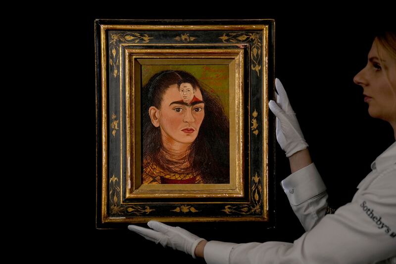 A staff member poses for photographs with the Mexican painter Frida Kahlo’s 1949 self-portrait “Diego y yo”, Diego and I, at Sotheby’s auction house in London, Thursday, Oct. 21, 2021. A new BBC documentary finds paintings by women sold for a tenth of what paintings by men sold for.