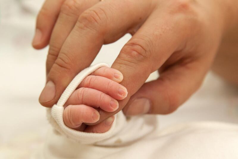 The baby clings to his father's finger