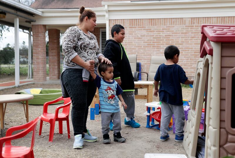 In this Friday, Jan. 11, 2019, photo, Maria Orbelina Cortez stands with her three sons, ages 11, 5, and 3, in the yard behind the Catholic Charities shelter in McAllen, Texas. Orbelina says that after fleeing El Salvador, she hopes to find refuge for her