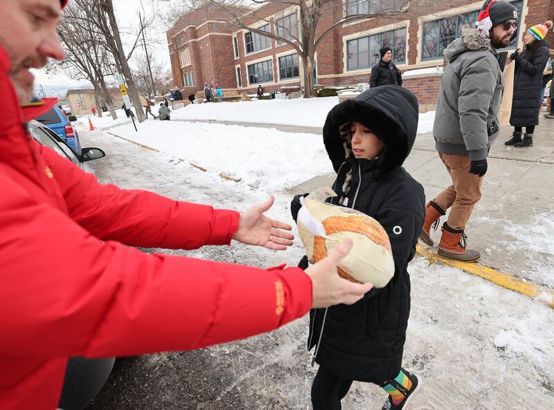 Volunteer Tal Lingstuyl carries a turkey to a car as Crossroads Urban Center distributes holiday food for 650 families.