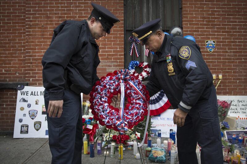 In this Monday, Dec. .22, 2014, file photo, members of the New Rochelle, N.Y. police department place a wreath at a makeshift memorial near the site where NYPD officers Rafael Ramos and Wenjian Liu were murdered in the Brooklyn borough of New York, Monday