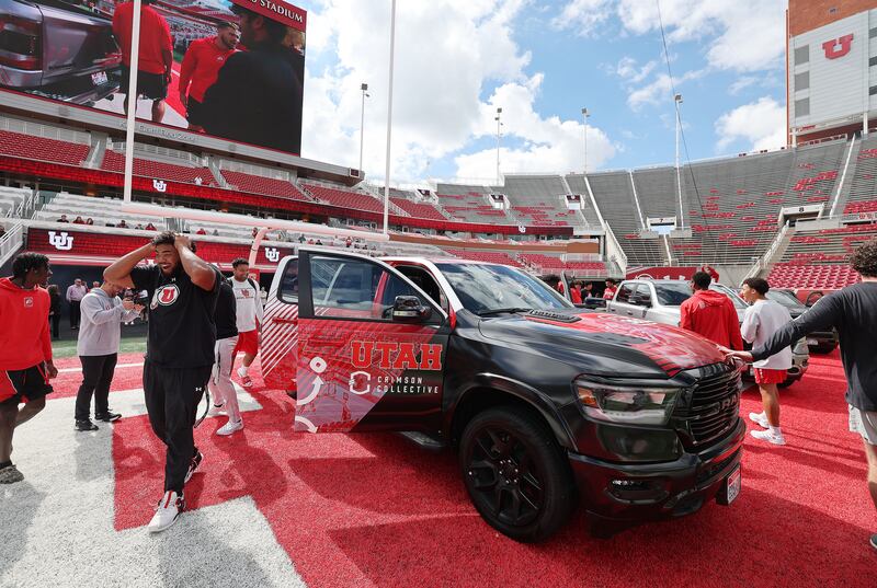 Utah Utes football players look over trucks.
