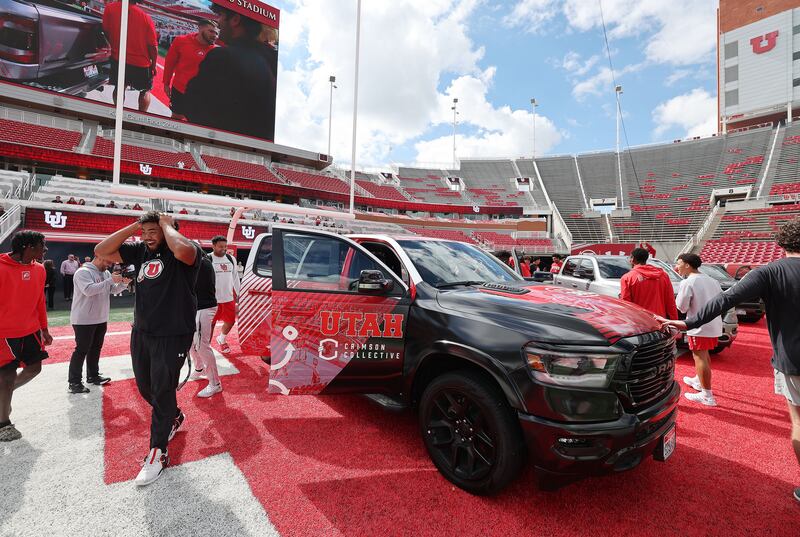Utah Utes football players look over trucks.