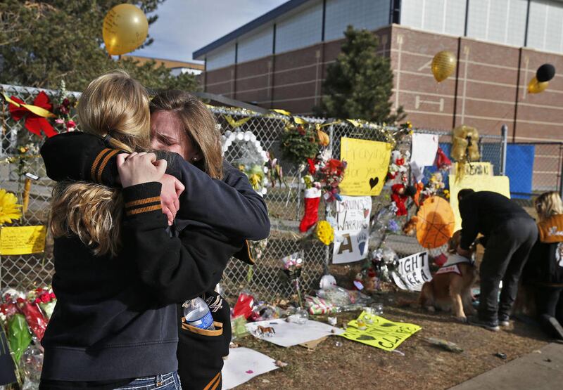 Arapahoe High School senior Lily Boettcher, right, and 2013 Arapahoe grad Joy Dafoe hug at a tribute site for severely wounded student Claire Davis, who was shot by a classmate during a school attack six days earlier at Arapahoe High School, in Centennial