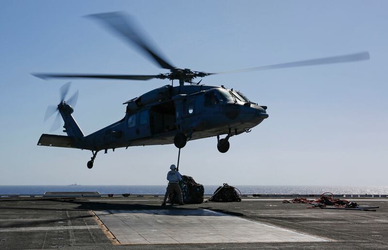In this Friday, May 10, 2019 photo released by the U.S. Navy, logistics specialists attach cargo to an MH-60S Sea Hawk helicopter on the flight deck of the Nimitz-class aircraft carrier USS Abraham Lincoln in the Persian Gulf. The aircraft carrier strike
