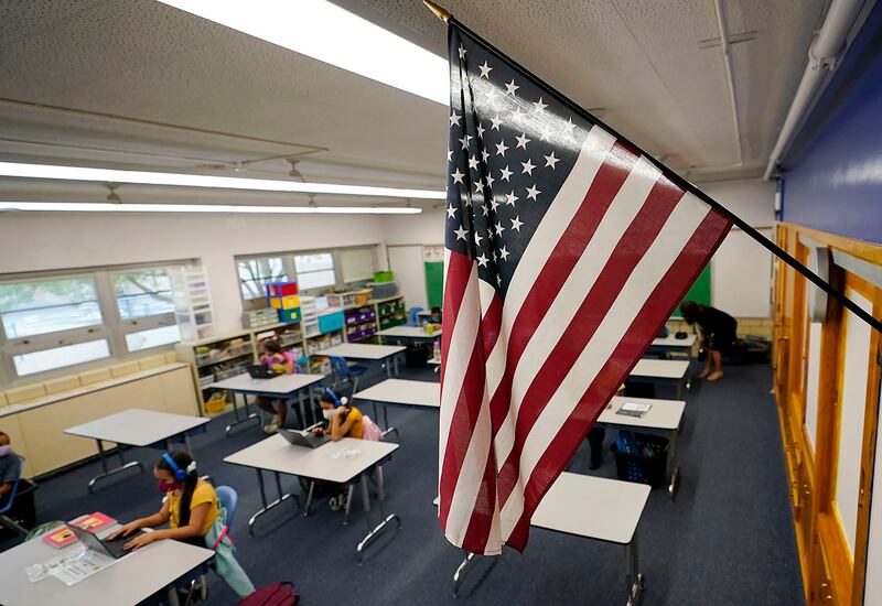 In this Aug. 25, 2020, file photo, an American flag hangs in a classroom as students work on laptops in Colorado.