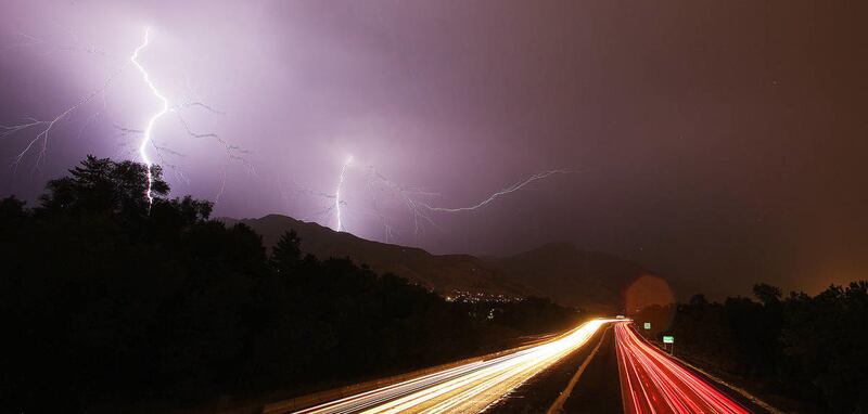 Motorists drive along I-80 in the rain as lightning strikes nearby in Salt Lake City August 22, 2013.