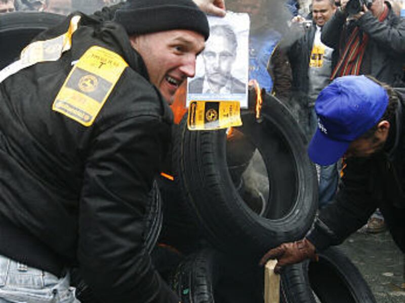 Employees of the Clairoix tire plant in France burn tires and a photo of plant director Louis Forzy during a demonstration Wednesday in Paris.
