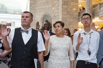 Nazil Pozegic, left, of Bosnia, Eva Bustos of Mexico and Loi Tran of Vietnam recite the Oath of Allegiance during a nationalization ceremony at the Utah State Capitol in Salt Lake City on Friday, Aug. 3, 2018. Citizenship was conferred on 110 people from
